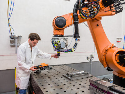Technologie Ein Mitarbeiter im weißen Kittel arbeitet an einer Maschine.