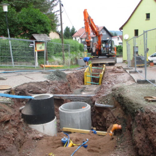 Ein Bagger setzt neue Abwassersysteme auf einer Baustelle.