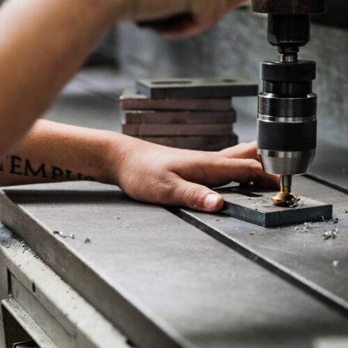 Auf einer Werkbank wird ein Metallteil bearbeitet.