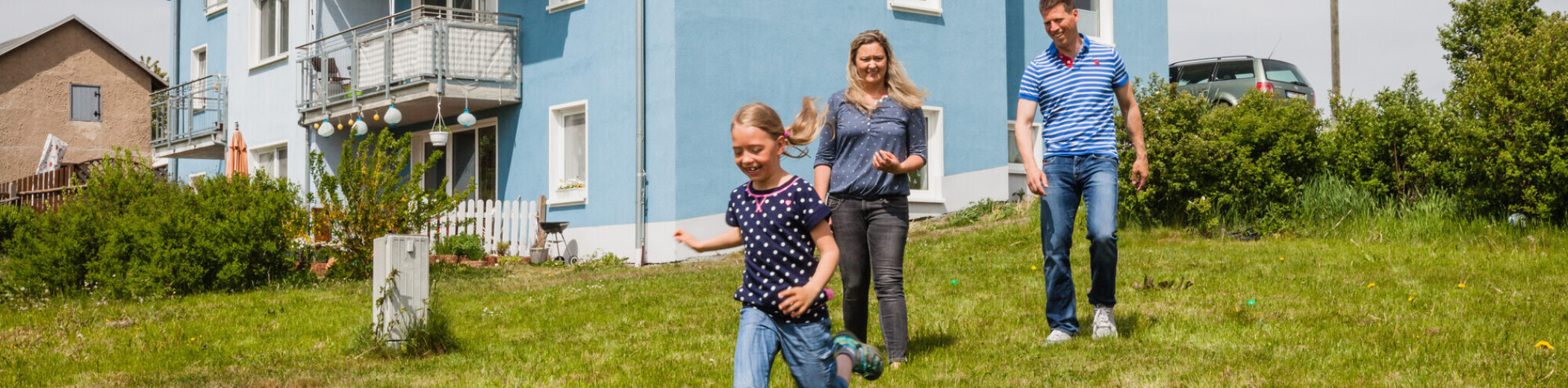 Eine Familie spielt Fußball im Garten des eigenen Hauses.
