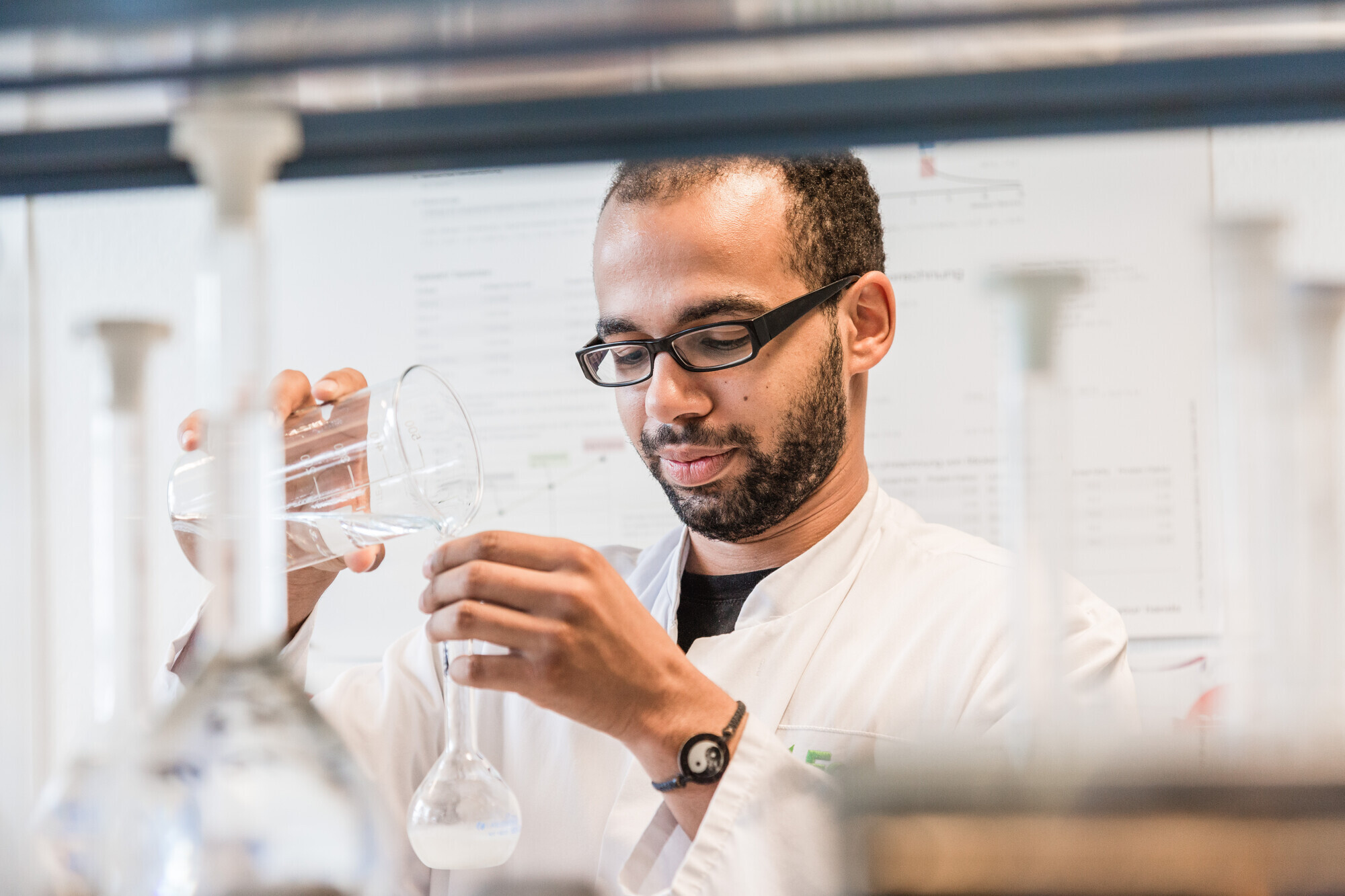 Ein Laborant gibt eine Flüssigkeit in ein Reagenzglas.