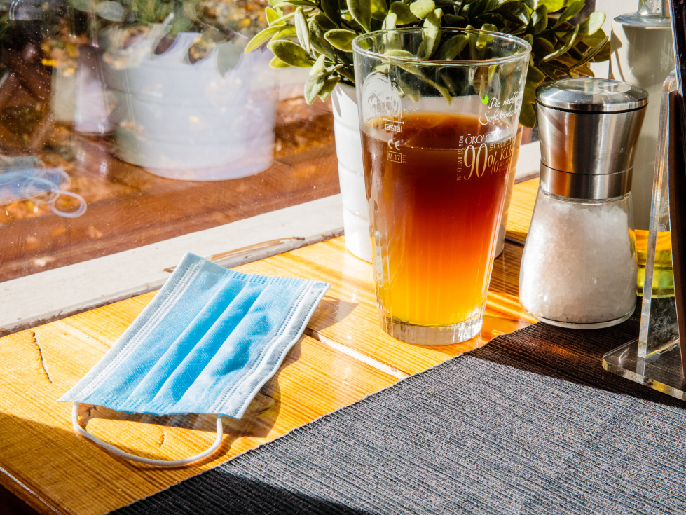 Neue Corona-Hilfen für temporäre Schließungen im November (im Bild: ein Mund-Nasen-Schutz auf einem Tisch neben einem Getränk).