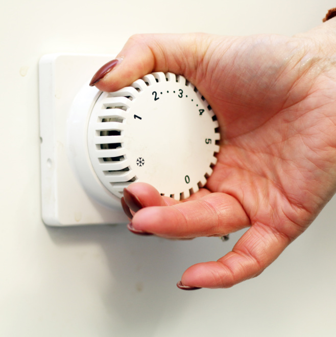 Hand dreht am Thermostat