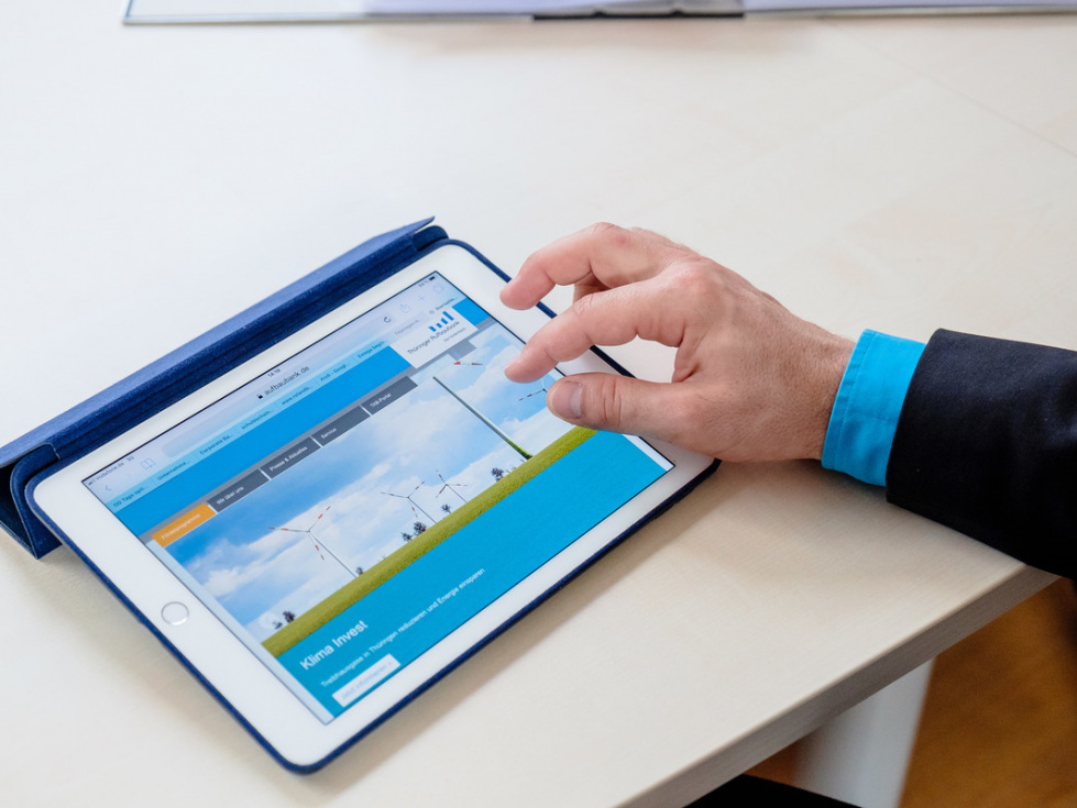 Informationen aus der Thüringer Aufbaubank (auf dem Bild zu sehen ist ein Tablet, das von einem Mann bedient wird.)
